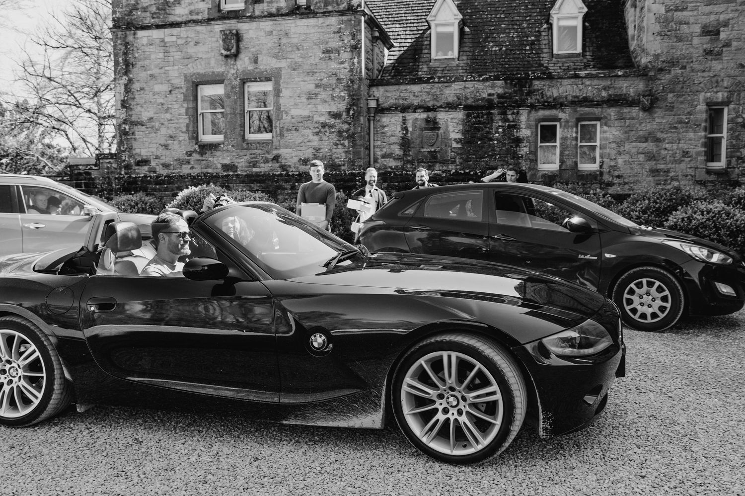 Castle Leslie Wedding Photographer Dublin Row of luxury black cars parked outside a stone building for a formal event.