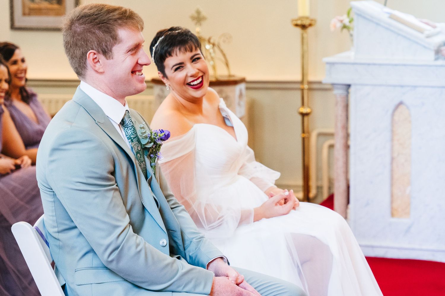 Millhouse slane wedding photographer dublin A couple shares a joyful moment during their wedding ceremony in a church.