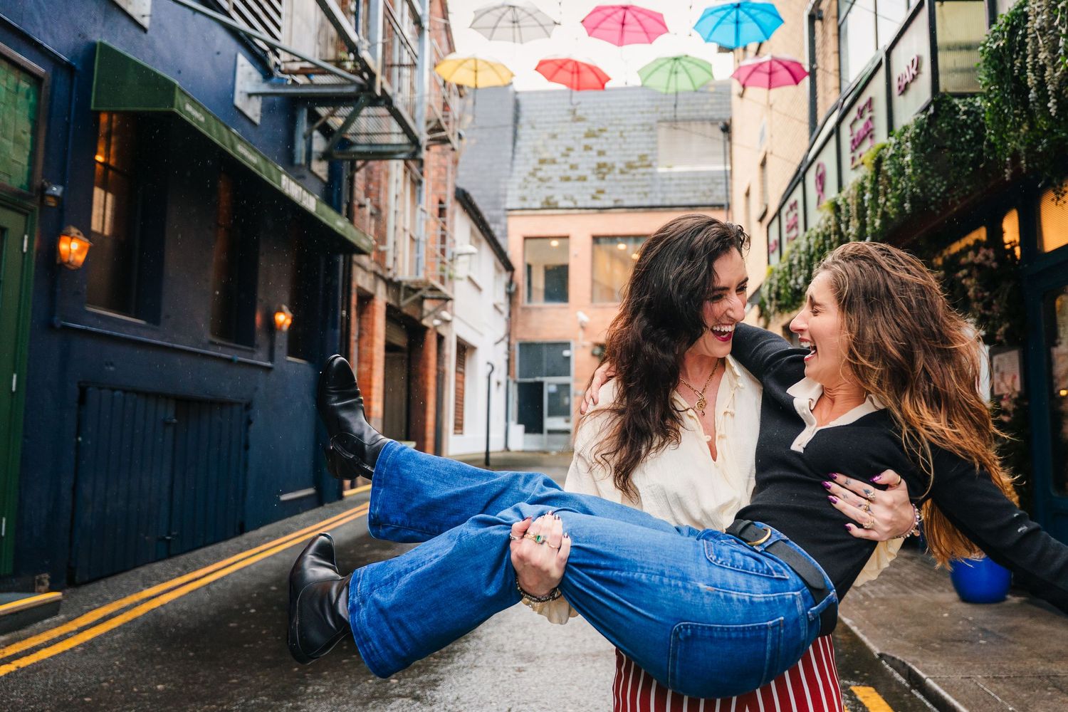Colorful umbrellas hanging above a cobblestone street while couple dances below. professional headshots dublin photographer