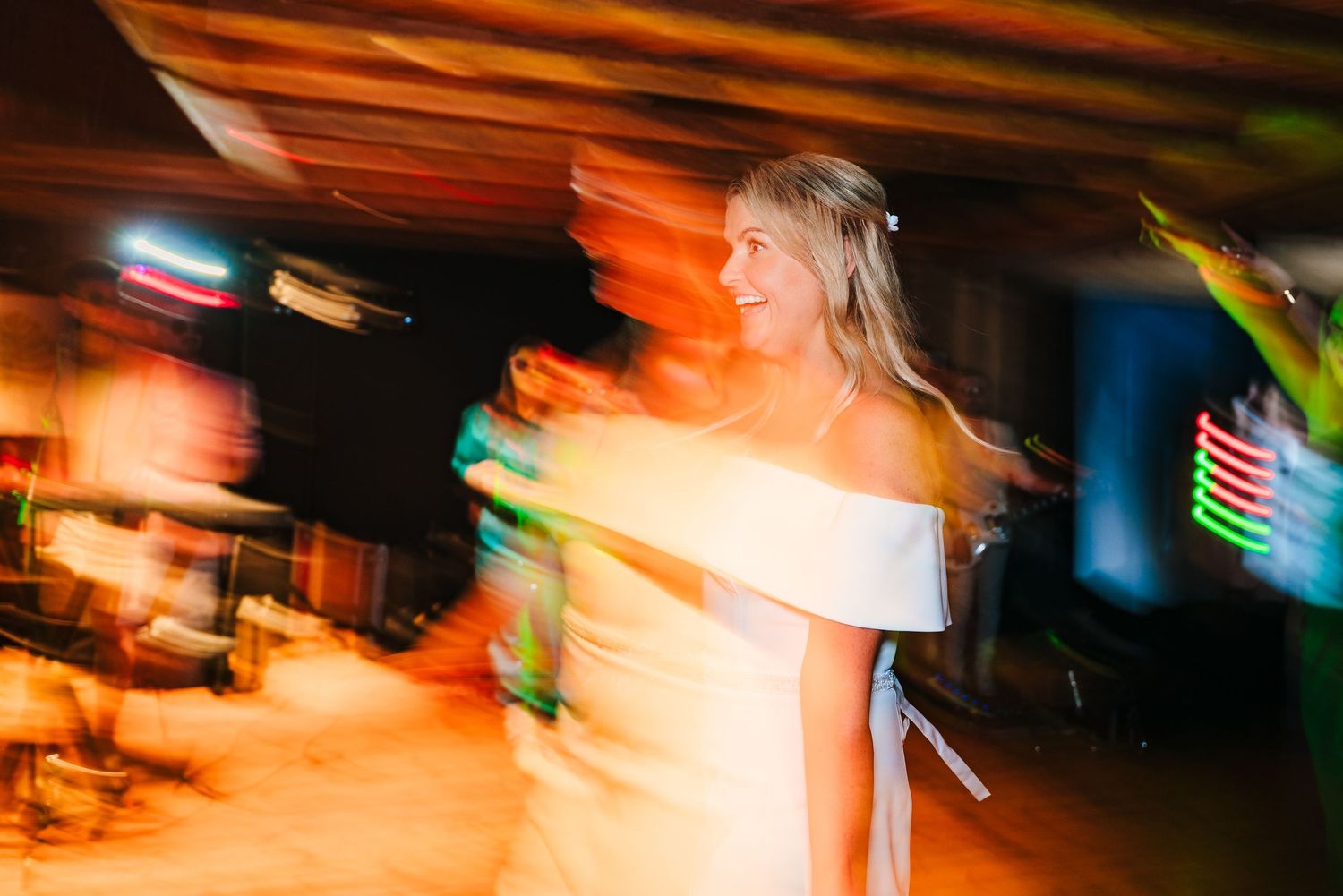 Motion-blurred photograph of people dancing at a party with colorful lighting effects. The Dean Dublin Wedding Photographer