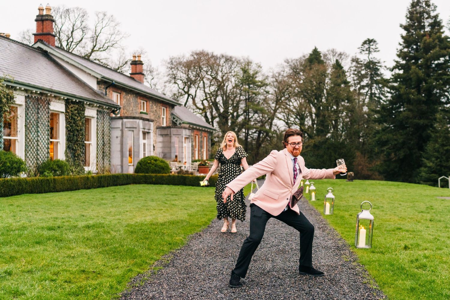 People walking and enjoying themselves on a grassy hillside near a historic building.  Virginia Park Lodge Wedding Photographer Cavan Dublin