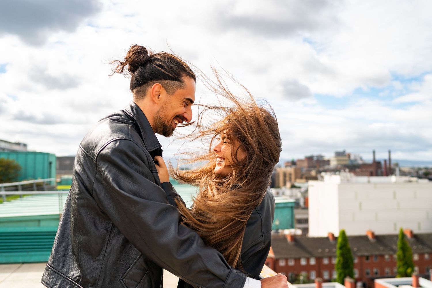 Wind-swept romantic moment on urban rooftop with city skyline in background. Couple's Photoshoot PHOTOGRAPHER Dublin