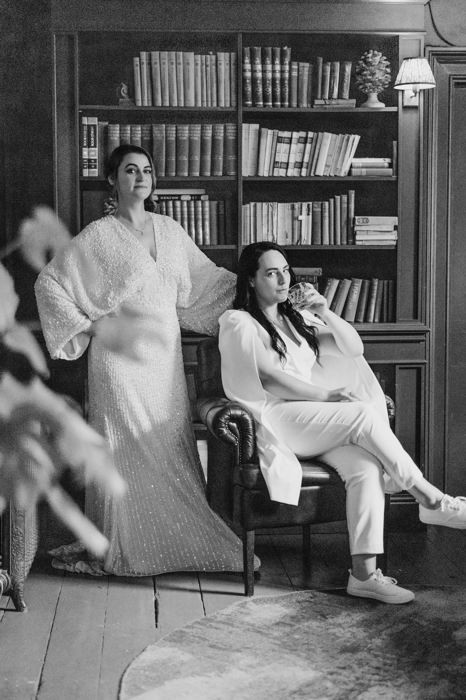 Two people in white clothing pose in a library room with floor-to-ceiling bookshelves. House Dublin Wedding Photographer