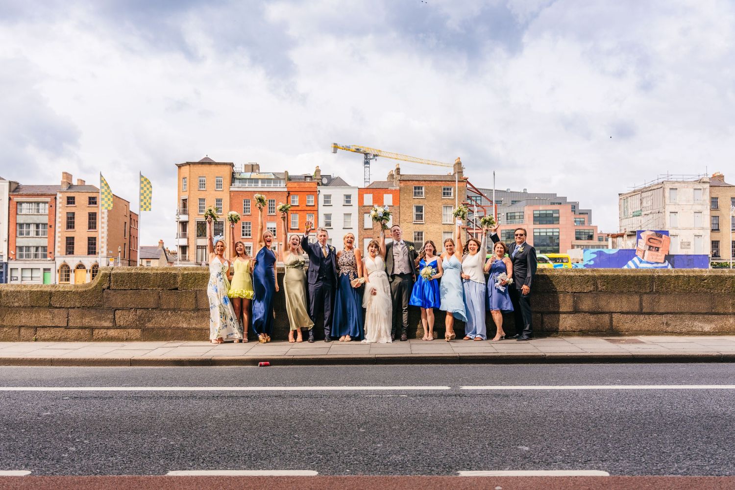 Group photo of wedding party on bridge with historic Dublin architecture in background. PHOTOGRAPHER Dublin Ireland Wedding