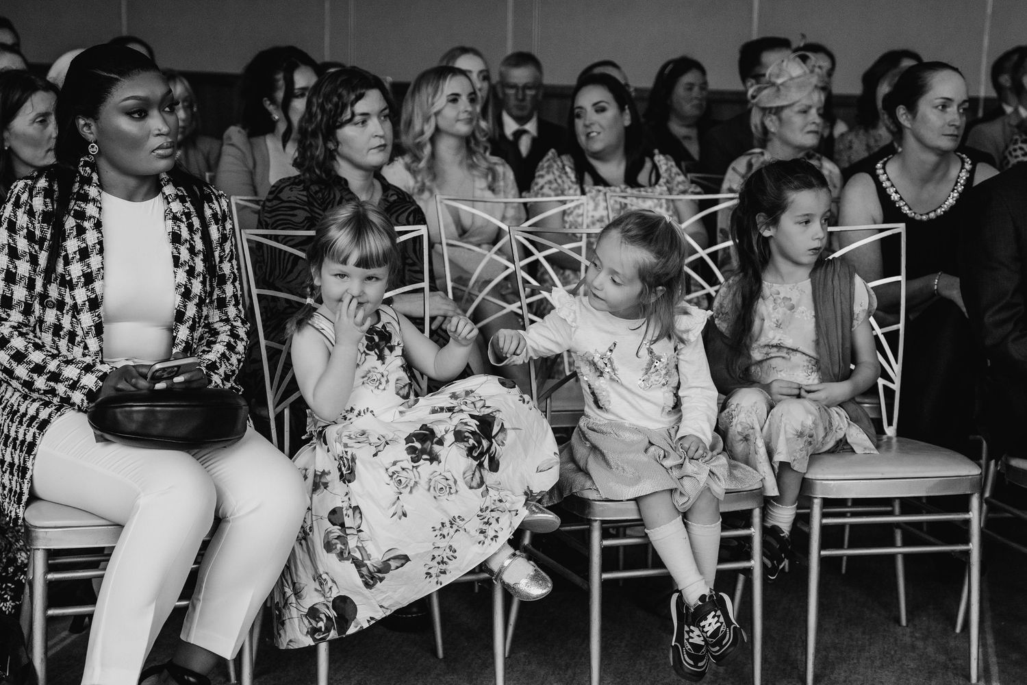 Black and white photo showing audience members seated in rows of chairs at an event. Wedding Photography Trim Castle Ireland