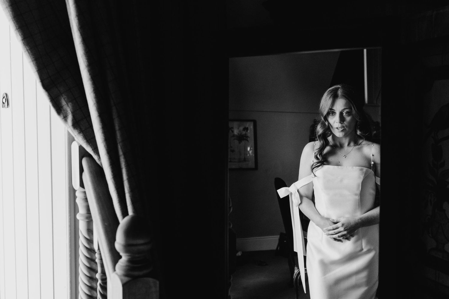 Castle Leslie Wedding Photographer Dublin Black and white photo of a bridal dress being fitted in a room with curtains.