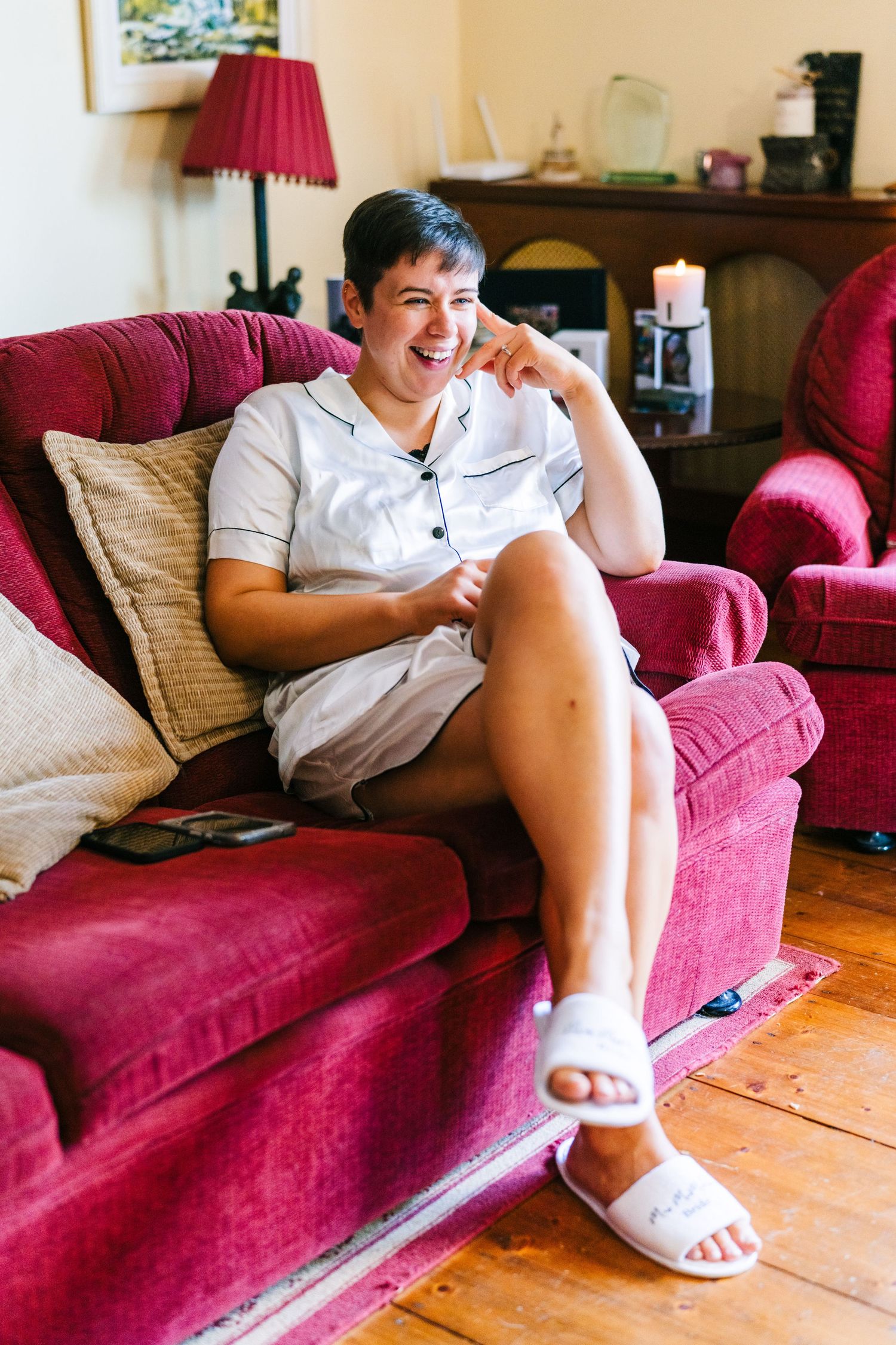 Millhouse slane wedding photographer dublin Person lounging casually on a burgundy couch in a bright living room wearing white clothing.