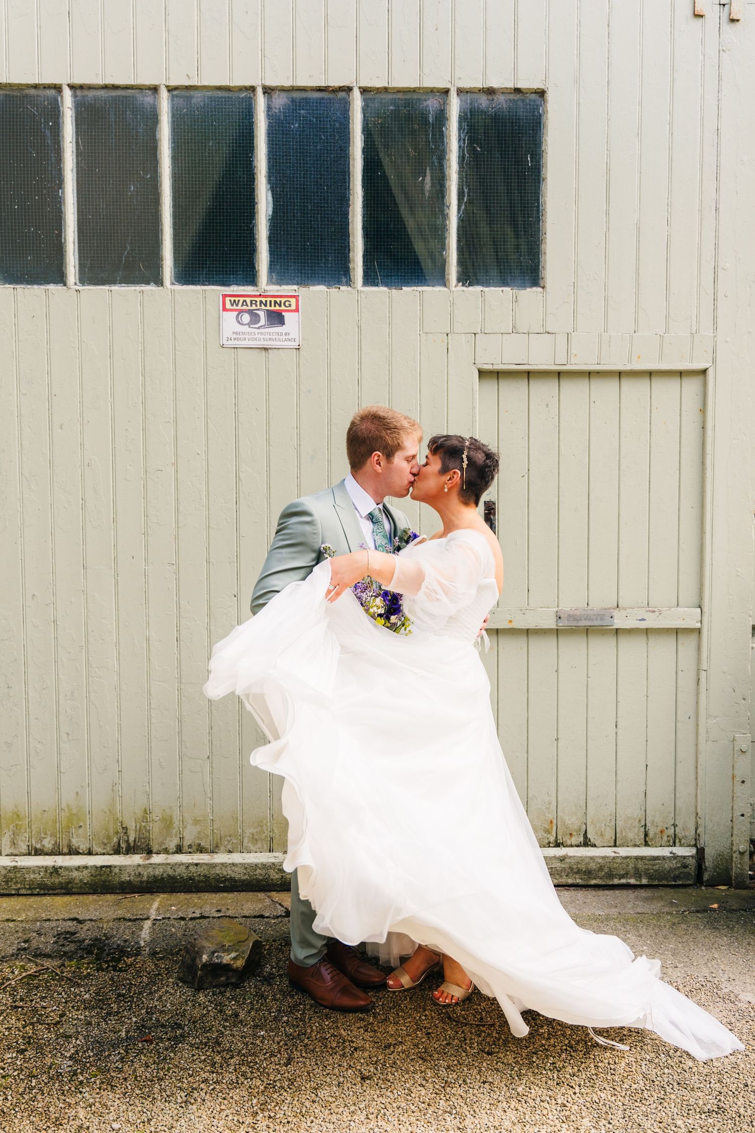 Millhouse slane wedding photographer dublin Playful wedding couple posing for photos against a rustic white barn wall.