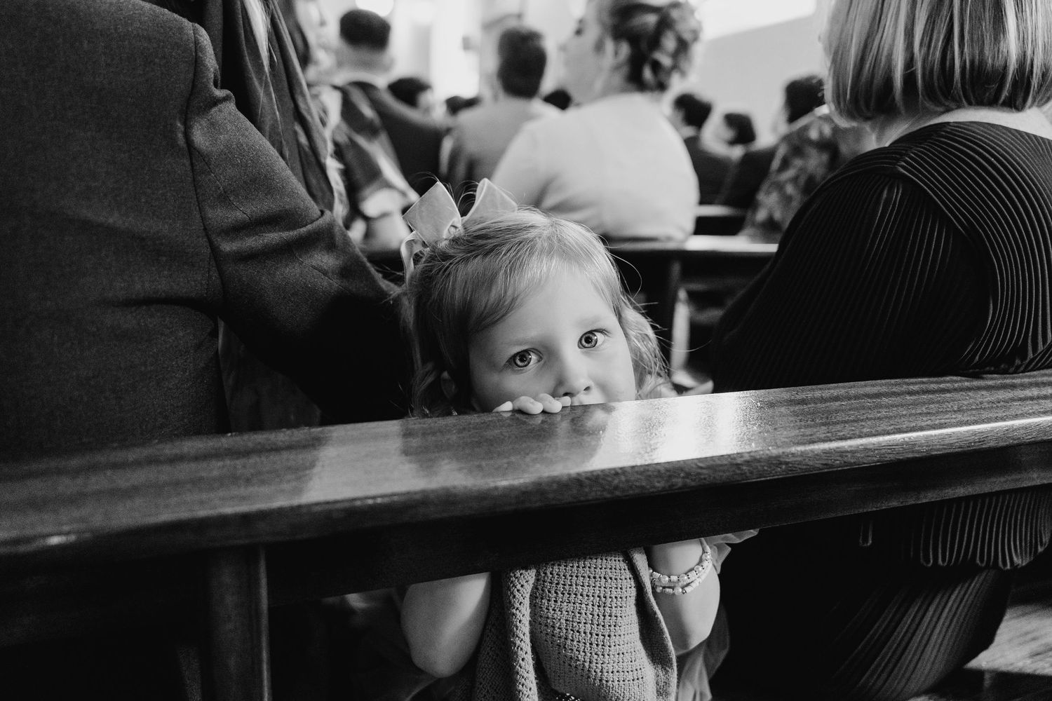 Millhouse slane wedding photographer dublin Black and white photo of a small child peeking over a wooden church pew.
