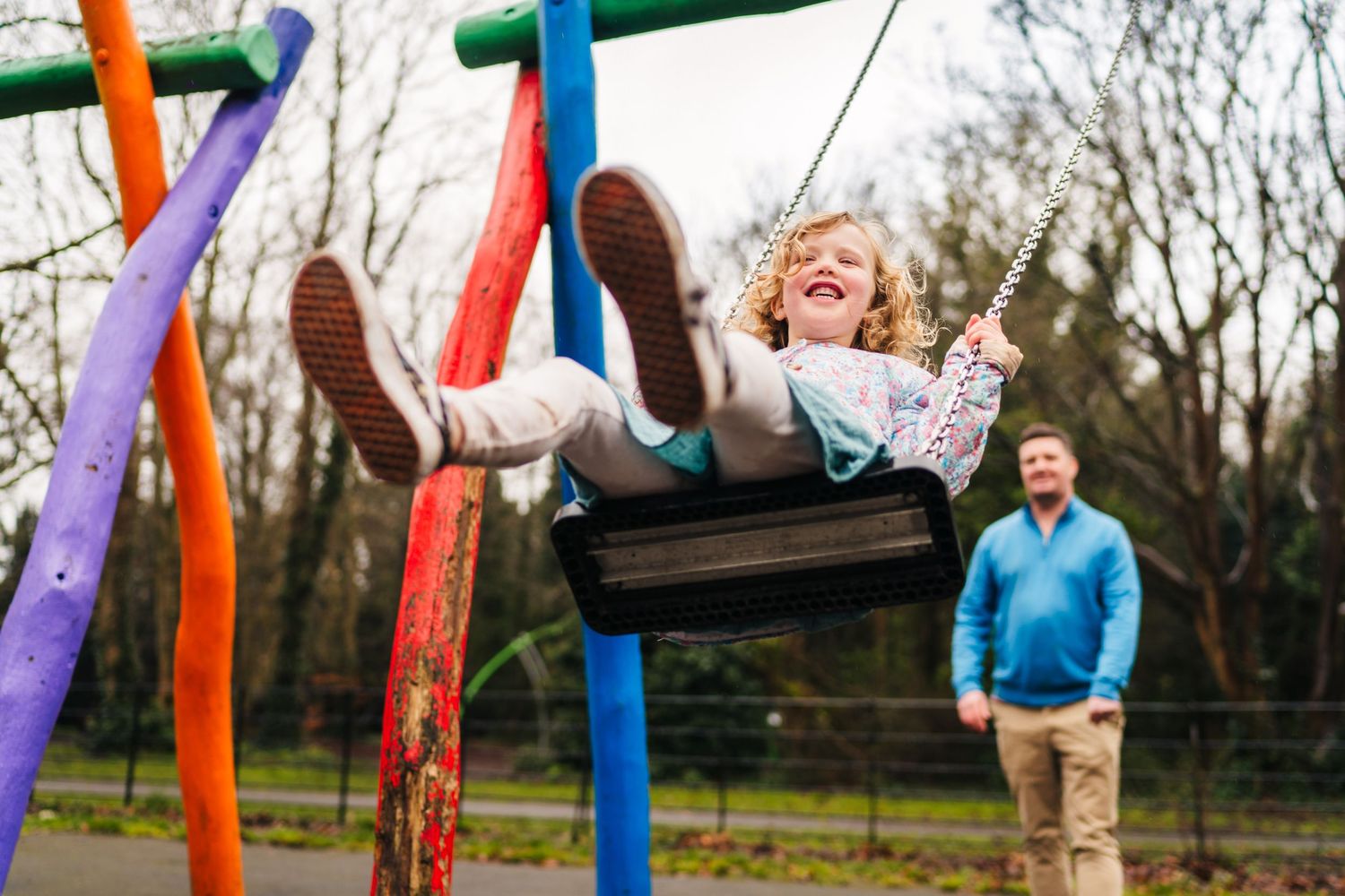 Family photographer Dublin Ireland  Dynamic playground scene with someone swinging high among colorful poles.