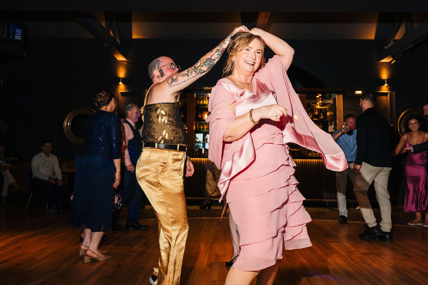 Poulaphouca Wedding photographer wicklow  Guests dancing and celebrating on a dimly lit dance floor at an evening wedding reception.