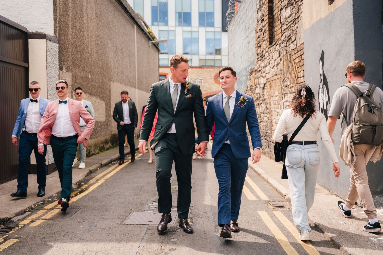 Wedding guests and party members walking down urban alleyway during celebration. Same sex wedding PHOTOGRAPHER Dublin