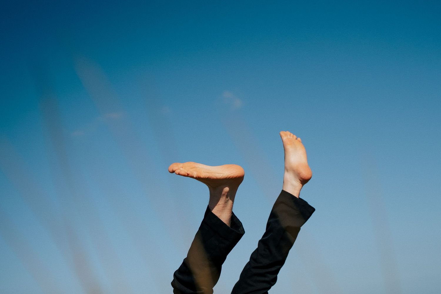 Bare feet in black pants kicked up against bright blue sky. PHOTOGRAPHER Dublin