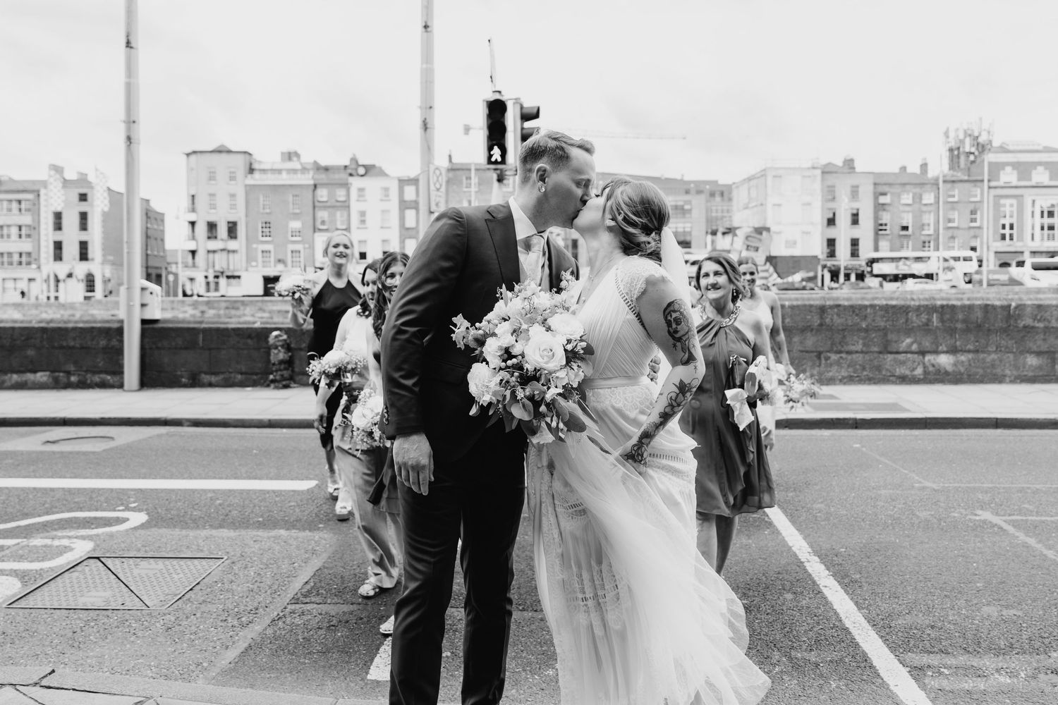 A wedding couple embracing on a city street in black and white photography. PHOTOGRAPHER Dublin Ireland Wedding