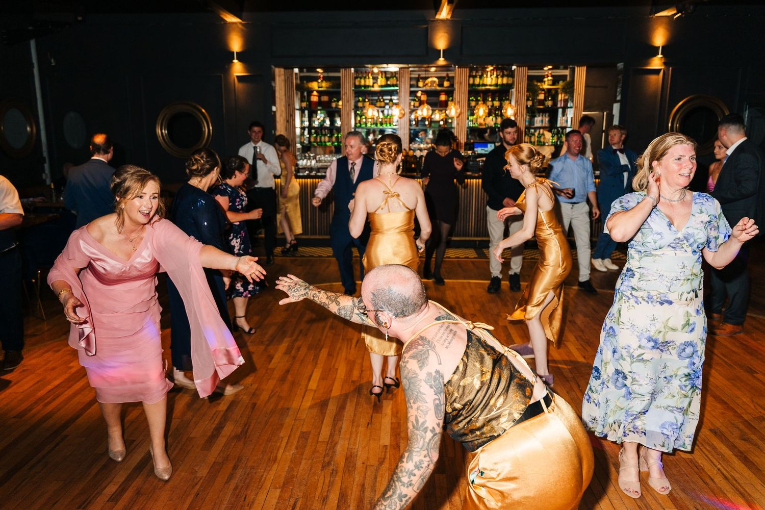Poulaphouca Wedding photographer wicklow  Evening wedding reception with guests dancing energetically on a warmly lit wooden dance floor.