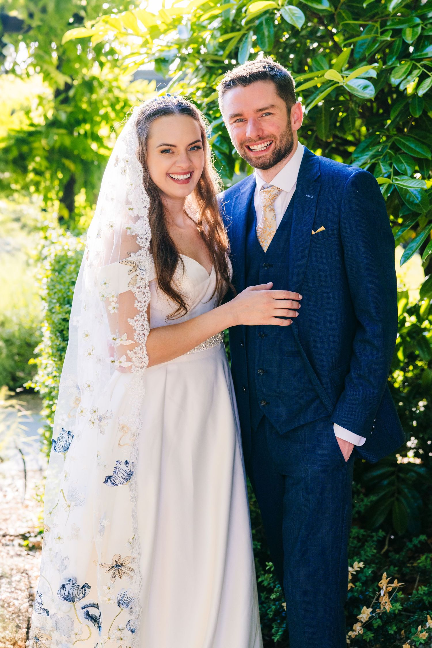 Poulaphouca Wedding photographer wicklow  Couple in wedding attire sharing joyful moments in a lush garden setting.