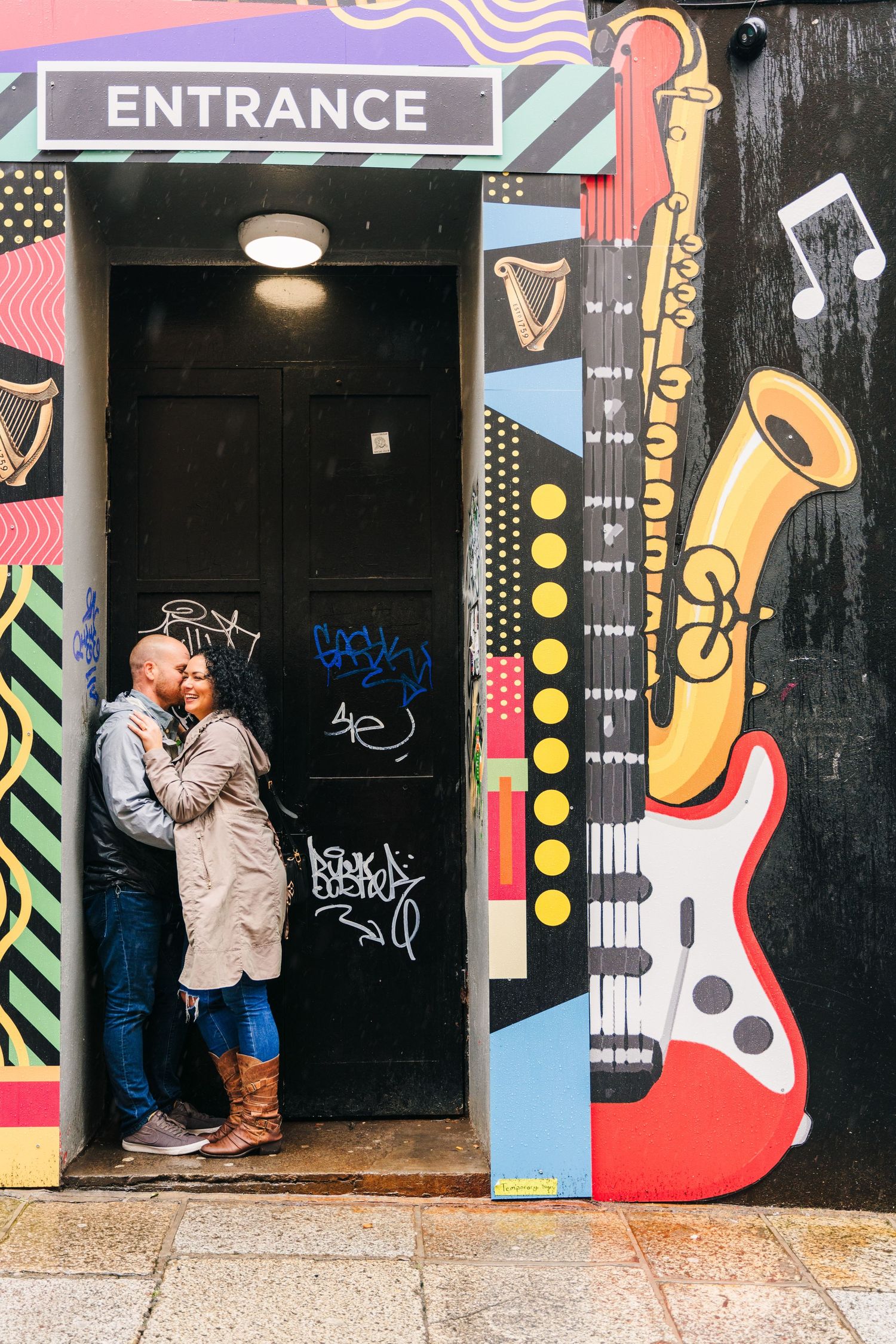 Colorful musical-themed street art and instruments painted on a wall surrounds an entrance door in Dublin. Proposal Dublin Photographer