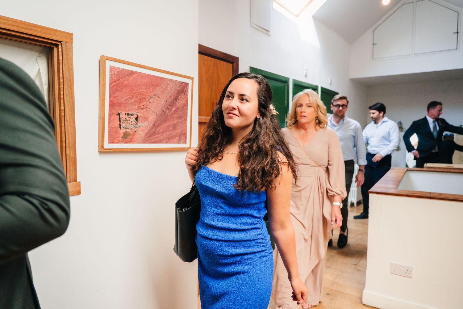 Wedding guests mingling in a bright indoor venue with wooden doorframes. Same sex wedding PHOTOGRAPHER Dublin