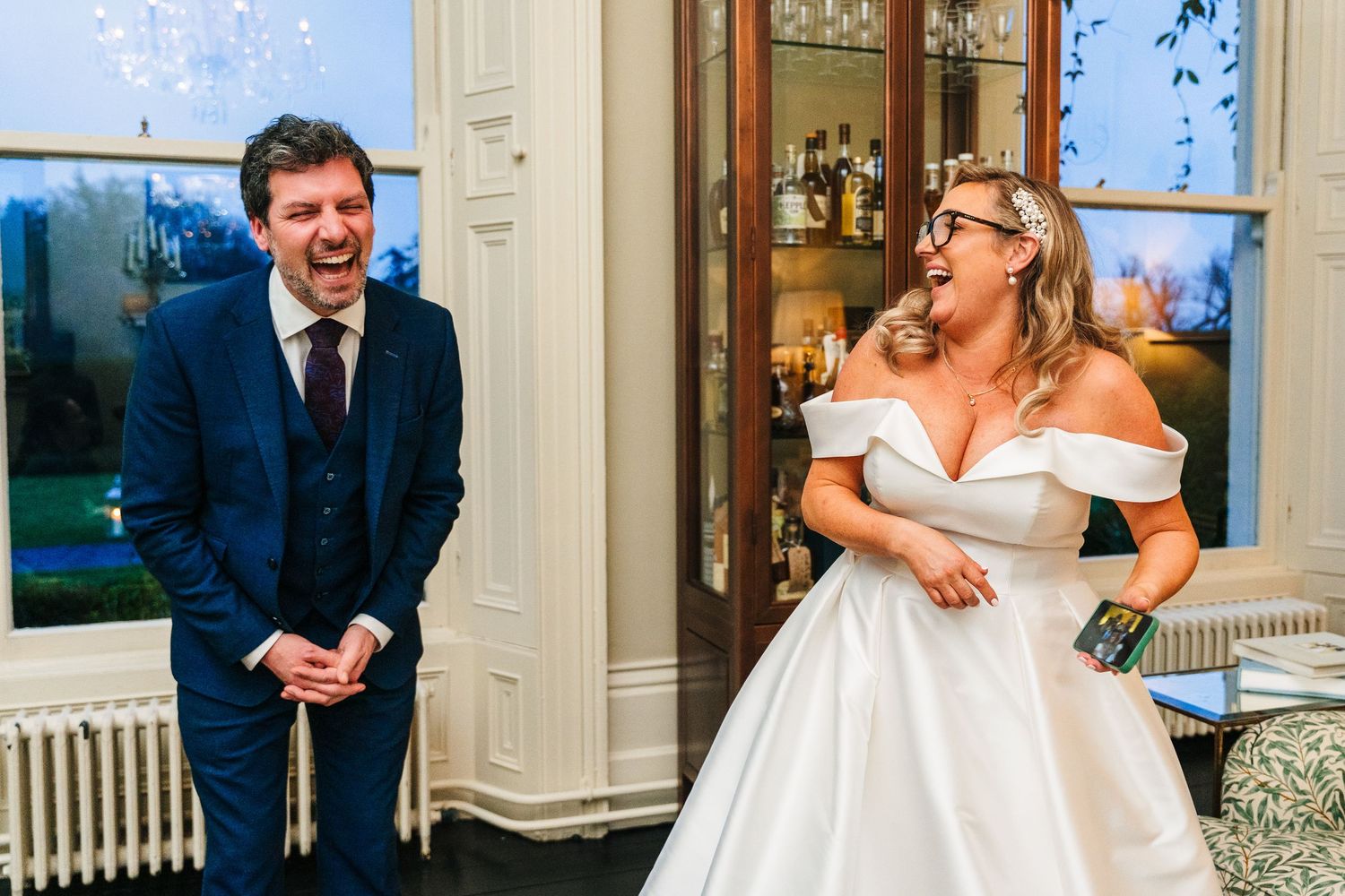 Wedding couple shares joyful and playful moments together in elegant venue with white decor.  Virginia Park Lodge Wedding Photographer Cavan