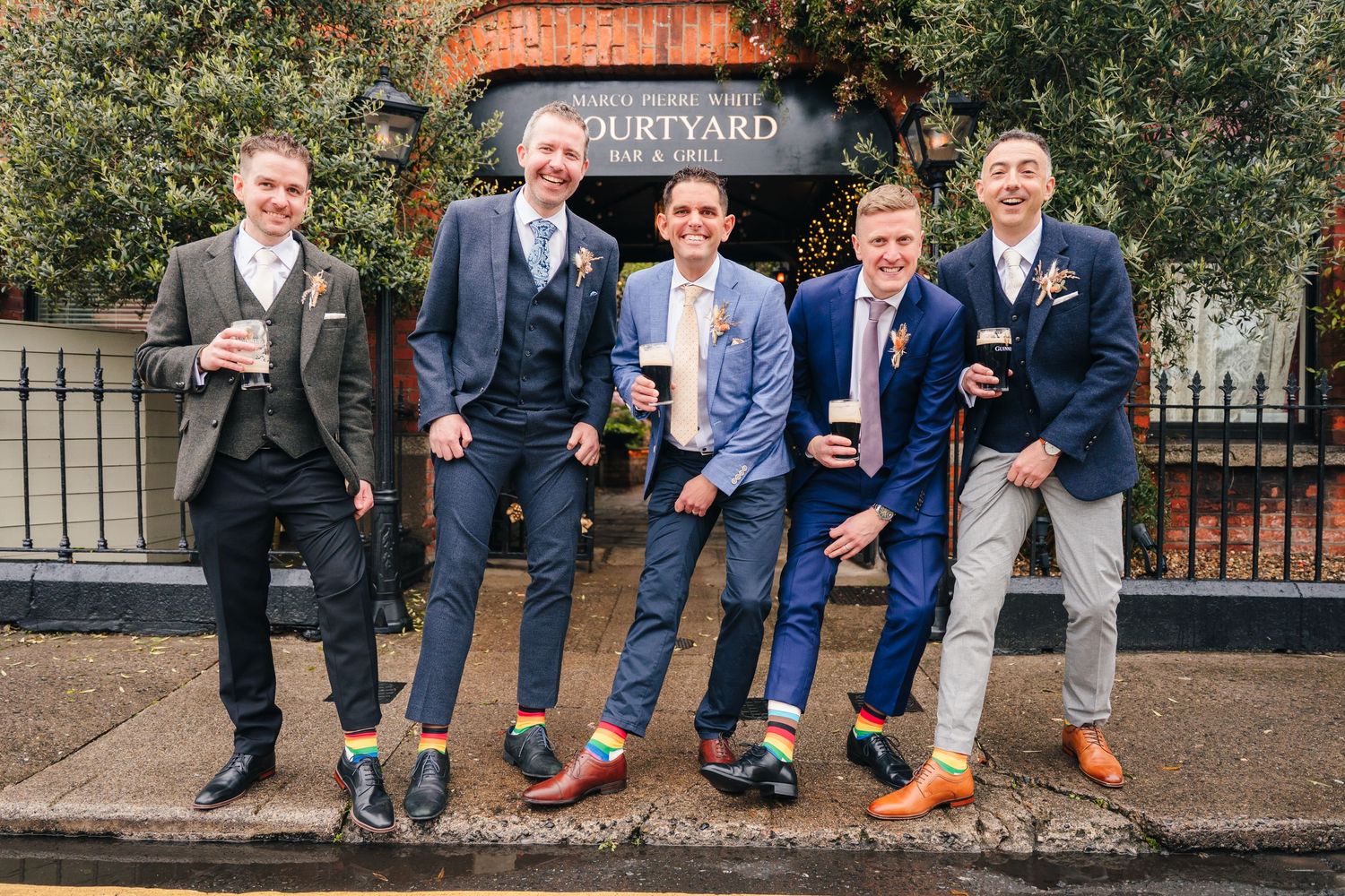 Five groomsmen posing with drinks outside The Courtyard venue in coordinated suits. Marco Pierre Dublin Wedding Photographer
