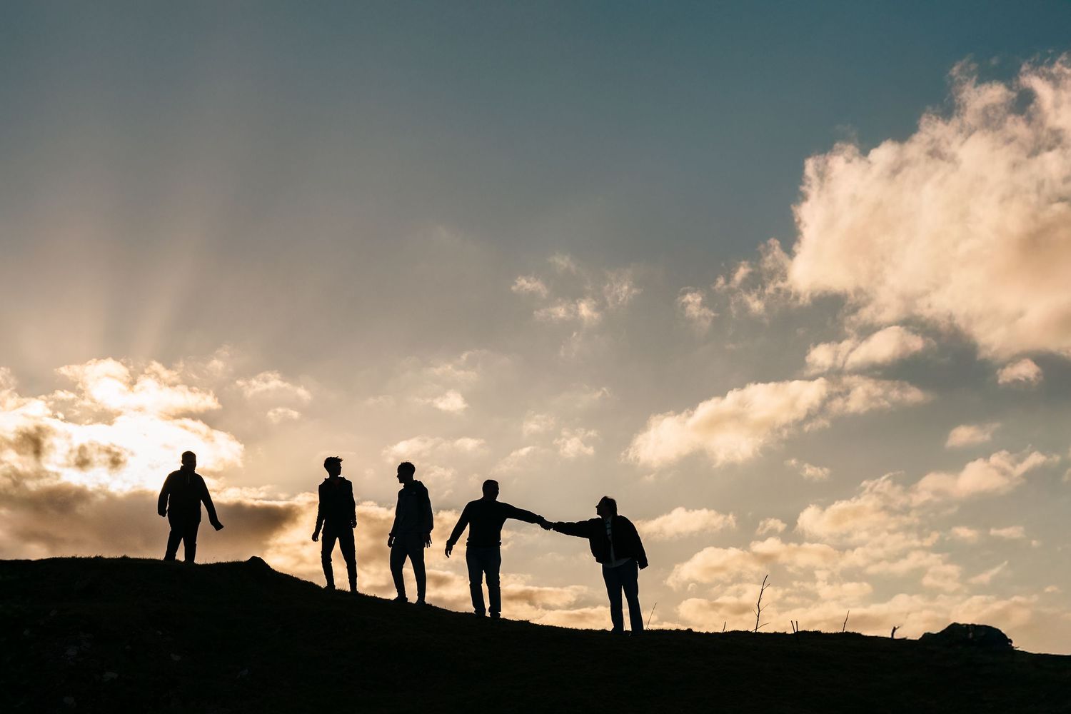 Silhouettes of five people standing on a hill against dramatic sunset sky and clouds. Family PHOTOGRAPHER Dublin