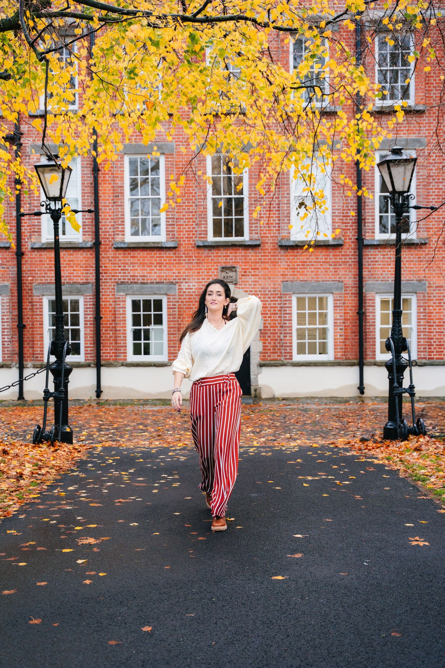 Street fashion photography on cobblestone path with fall leaves and historic architecture. professional headshots dublin photographer