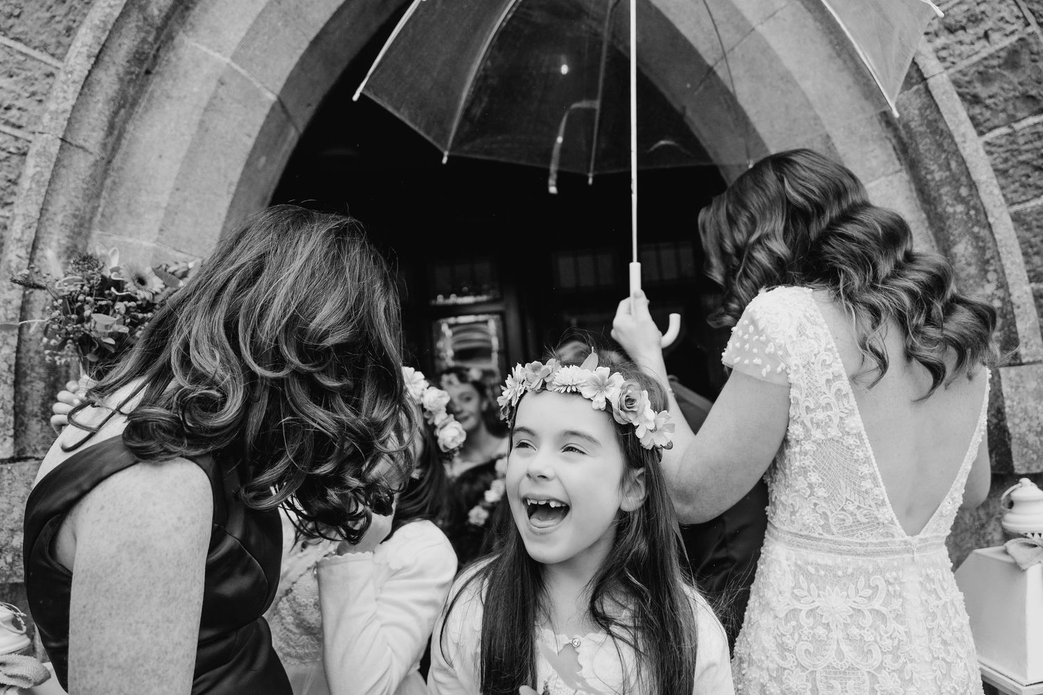 Black and white photos of joyful wedding moments under stone archways.