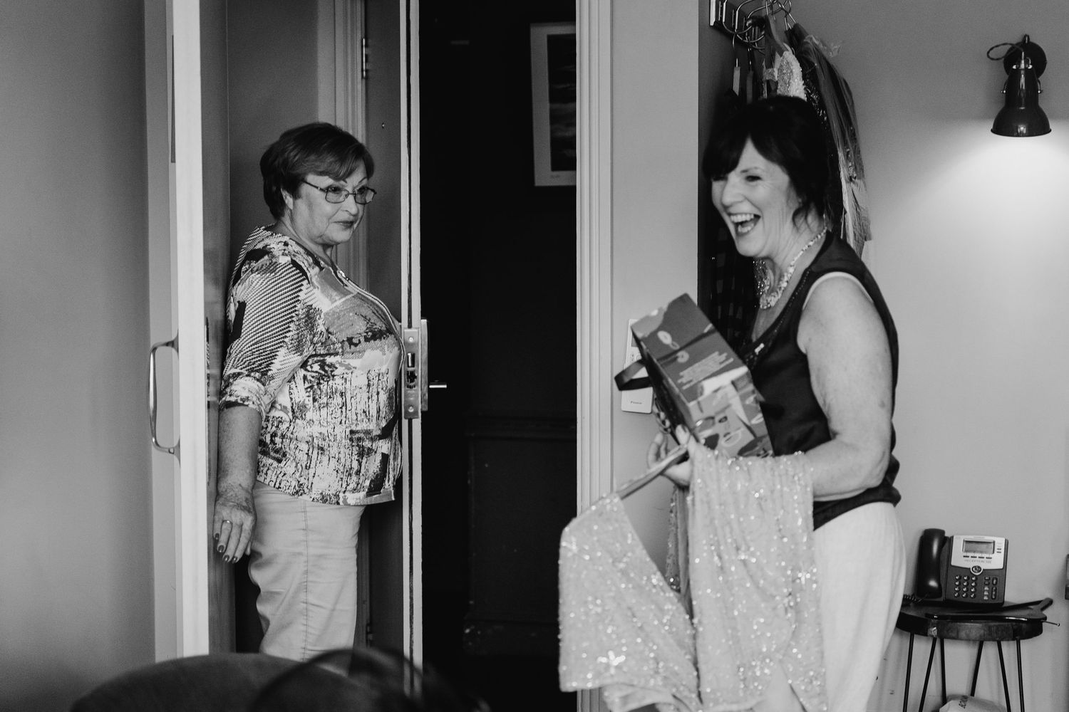 Two people laugh and smile while standing in a doorway, captured in black and white photography. House Dublin Wedding Photographer