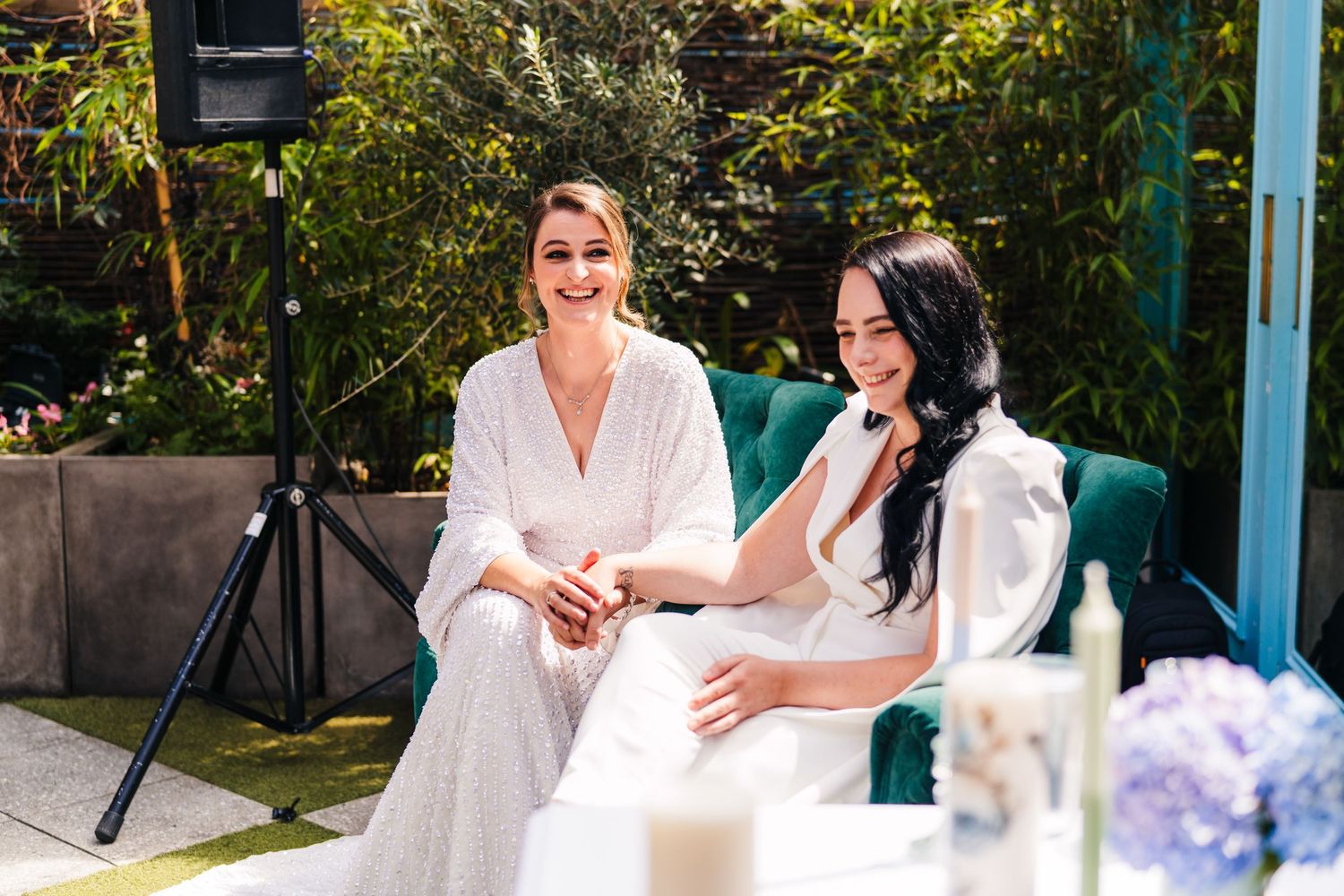 Two people in white outfits sit in a garden setting with purple flowers. House Dublin Wedding Photographer