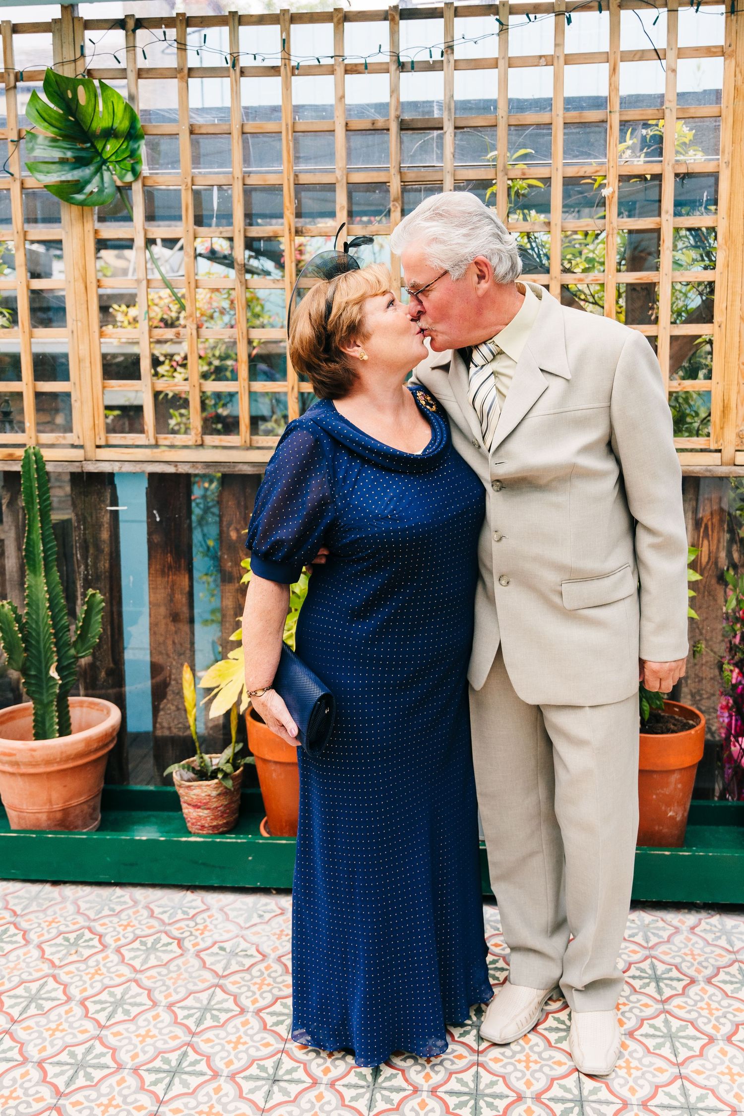 A couple shares an intimate moment in front of a wooden lattice with potted plants. House Dublin Wedding Photographer