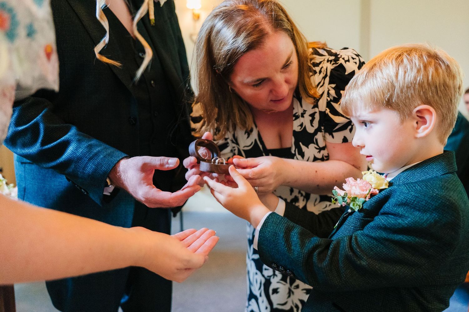A group gathers around to examine something small being passed between hands. . Village Barn Tyrrellspass wedding photographer Ireland