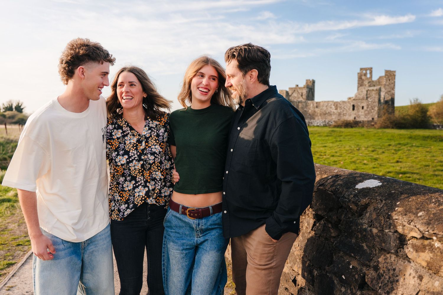 A group of four friends laugh together while standing near an ancient castle on a sunny autumn day. Photographer Ireland dublin