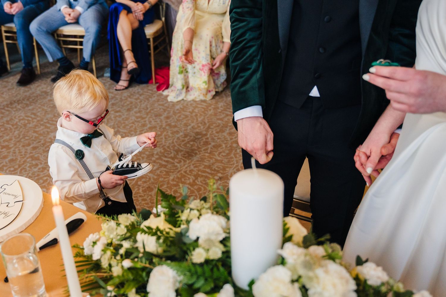 Wedding reception detail with white candle and floral arrangements on table.