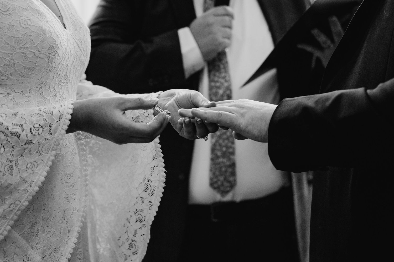 Close-up of hands exchanging rings during wedding ceremony in black and white. Wedding Photography Trim Castle Ireland