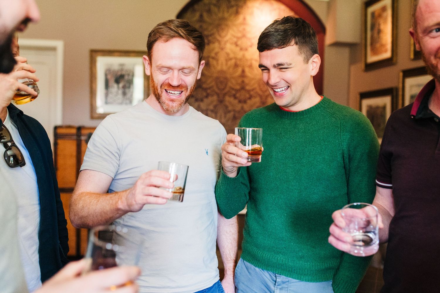 People sharing drinks and laughing together during a casual indoor gathering. Castle Leslie Wedding Photographer Dublin