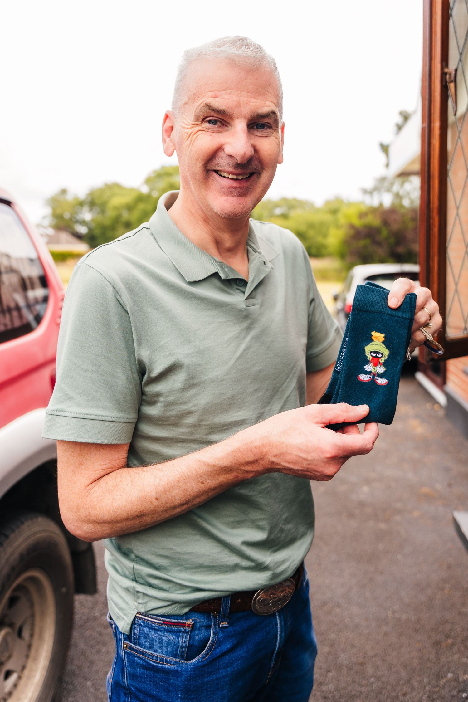 Millhouse slane wedding photographer dublin A person wearing a sage green polo shirt holding up a phone case outdoors.