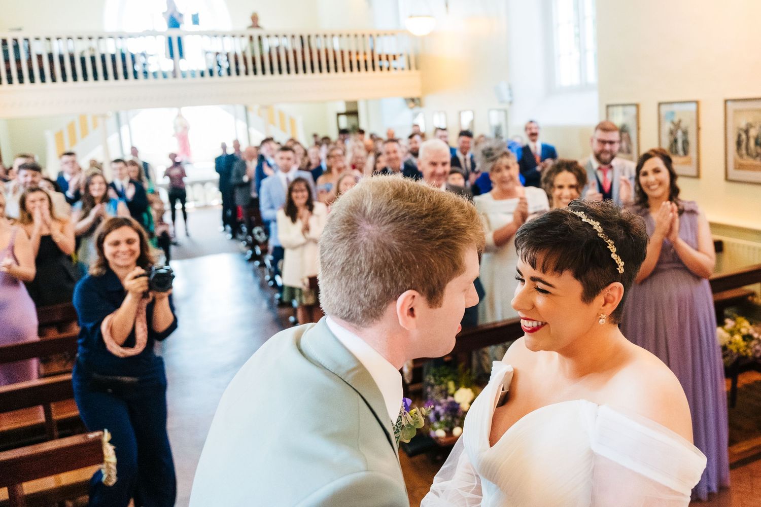Millhouse slane wedding photographer dublin Celebratory moment in church with guests applauding during wedding ceremony.