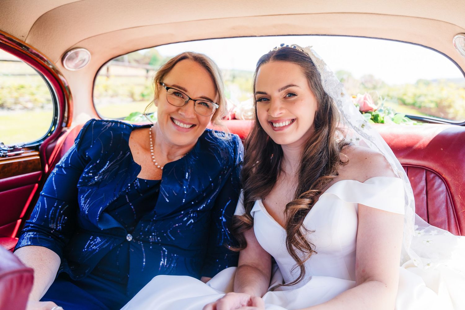Poulaphouca Wedding photographer wicklow  Bride and companion sitting together in vintage car interior.