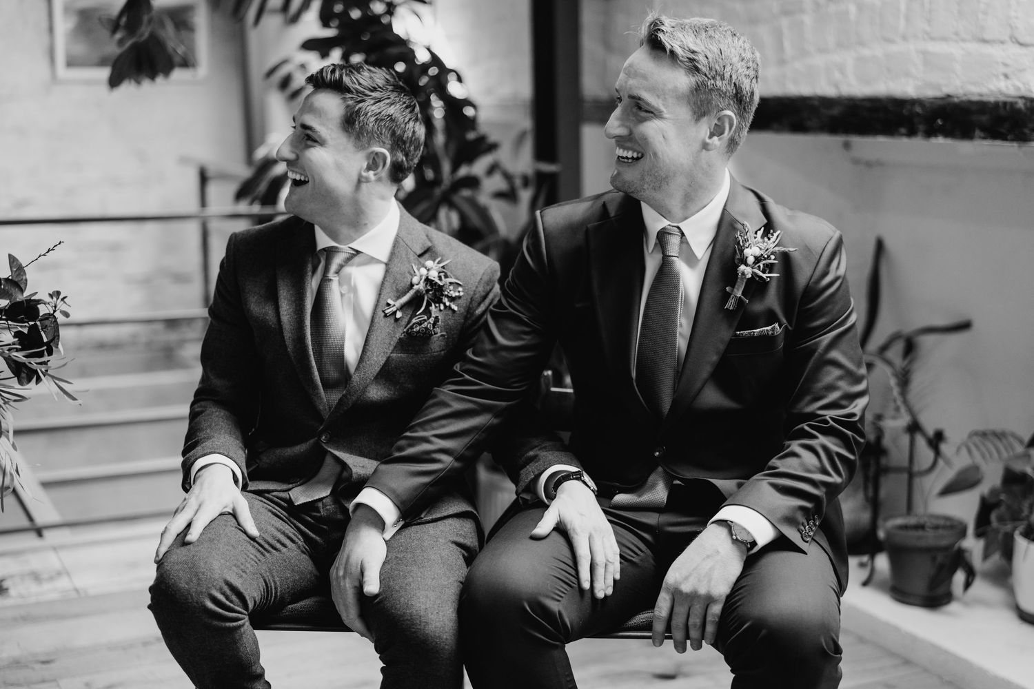 Groomsmen in formal black suits sharing candid moments on stone steps. Same sex wedding PHOTOGRAPHER Dublin