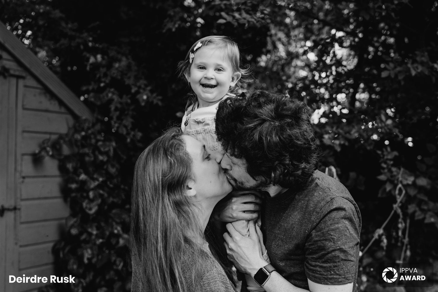 A joyful family moment captured in black and white as parents lift their small child outdoors. PHOTOGRAPHER Dublin
