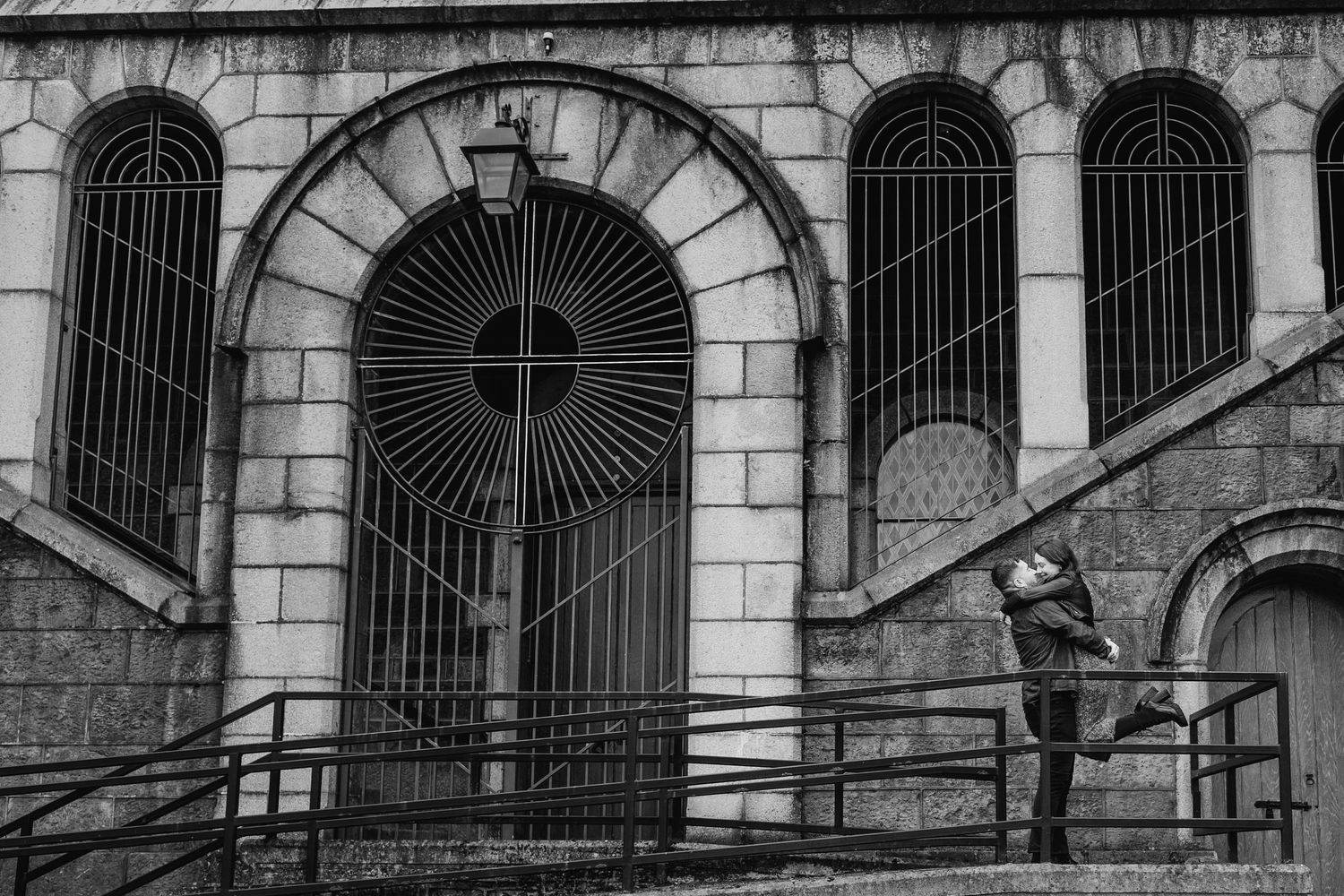 A silhouetted figure stands on a railing outside an ornate church entrance with arched windows and iron gates. PHOTOGRAPHER Dublin ireland