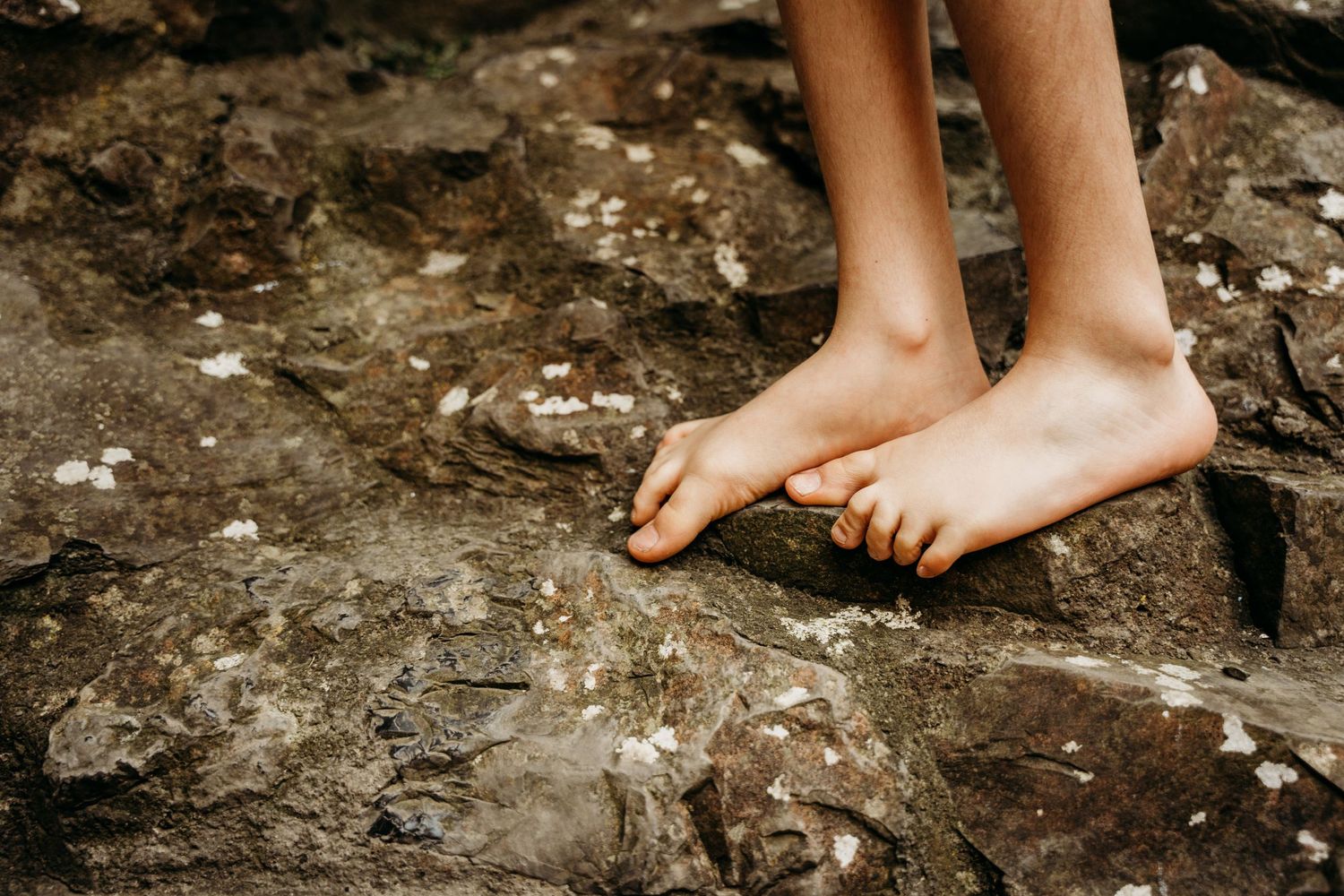 Bare feet balanced on rough rocky terrain with warm sunlight casting shadows. family PHOTOGRAPHER Dublin