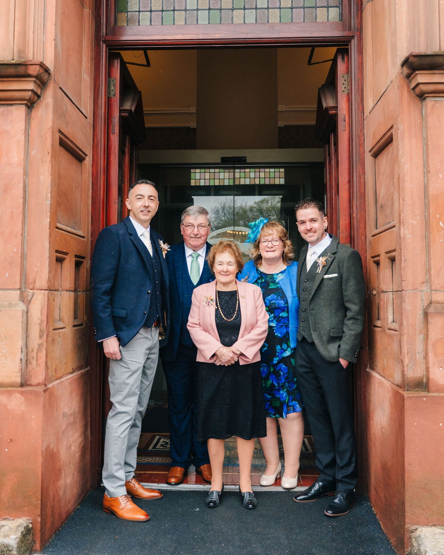 Wedding guests gather and pose in the doorway of a historic red brick building entrance. Marco Pierre Dublin Wedding Photographer