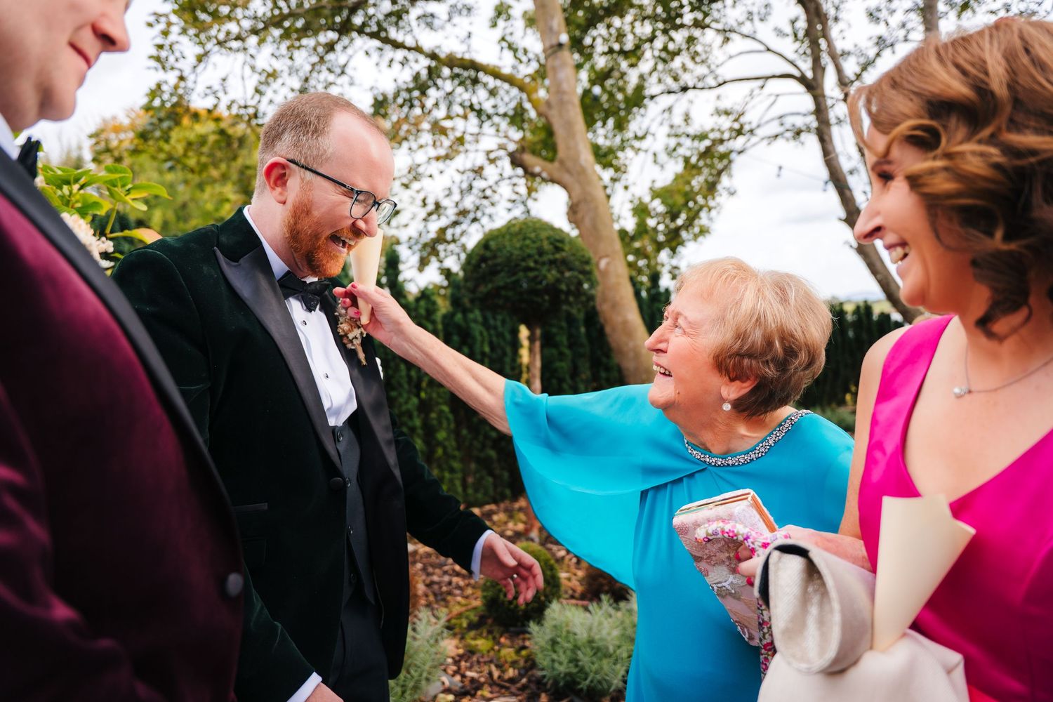 A candid moment of laughter and joy shared between wedding guests in a garden setting. LGBTQ Ashley Park Wedding Photographer