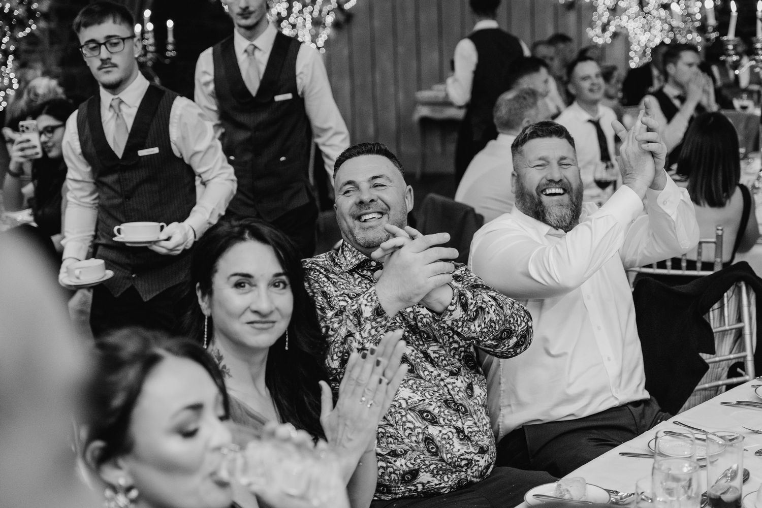 Black and white photo of wedding guests laughing and celebrating during reception dinner. Ballymagarvey Wedding photographer