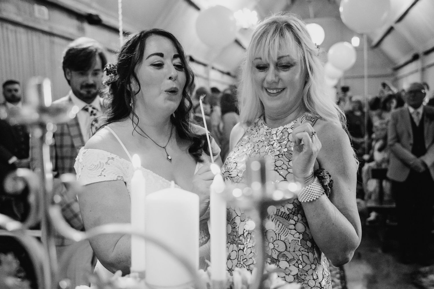 Wedding party celebrates during reception under white balloons and string lights. Wedding photographer Dublin