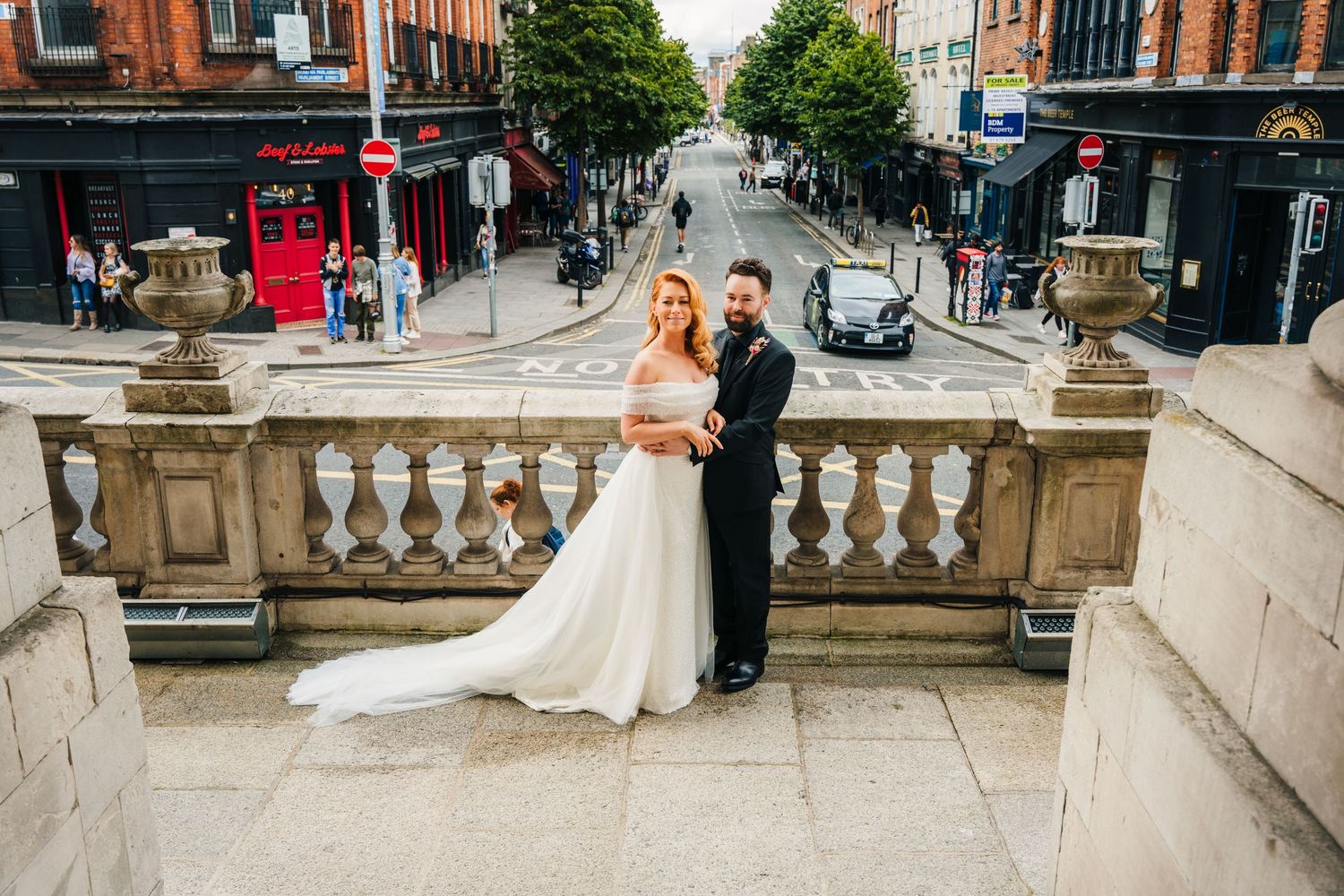 Wedding couple walking along a historic street with red brick buildings in the background.  city hall dublin wedding photos