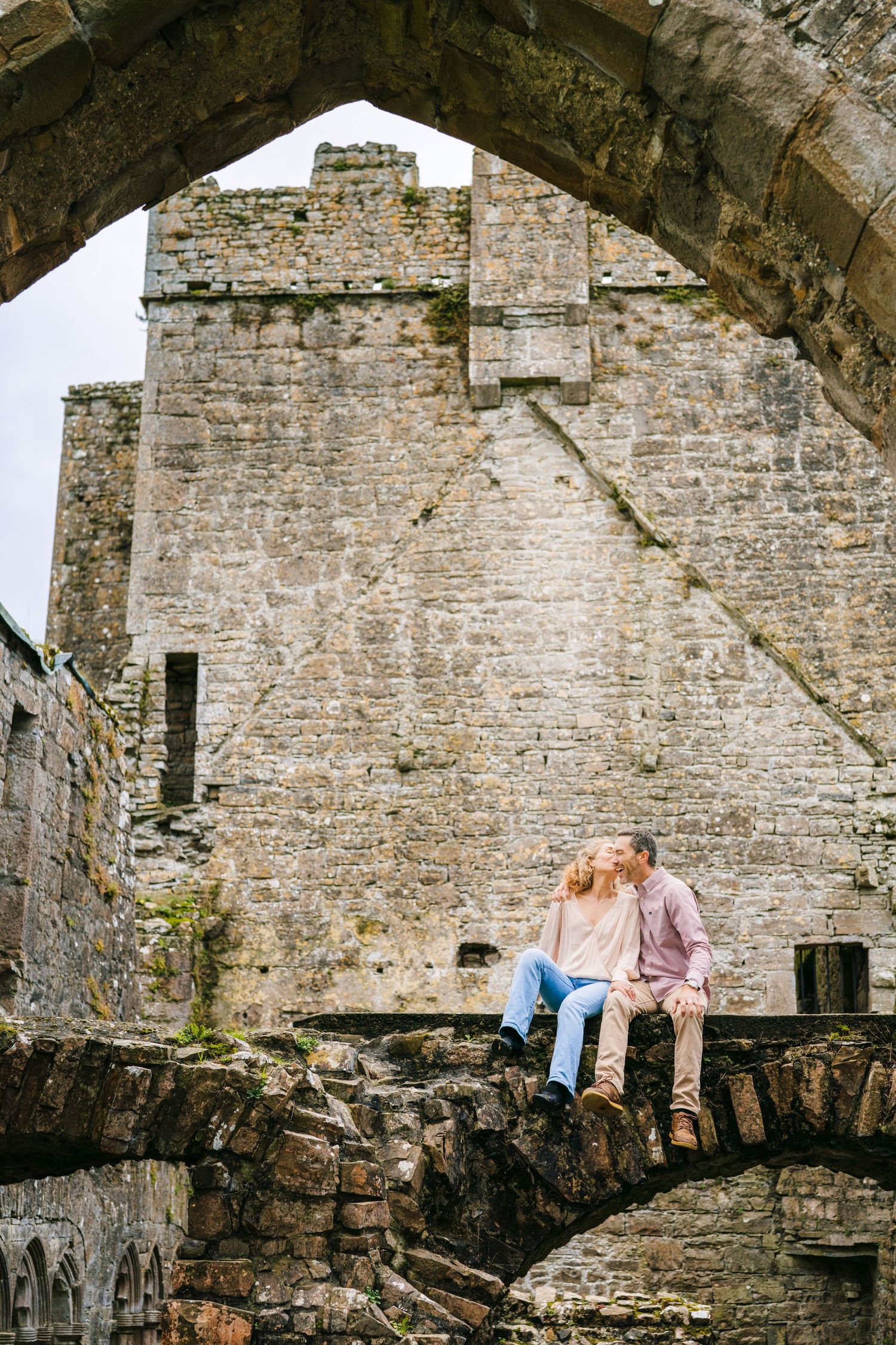 Stone castle ruins with weathered walls and arched openings create a dramatic architectural backdrop. BEctive abbey family photographer dubl