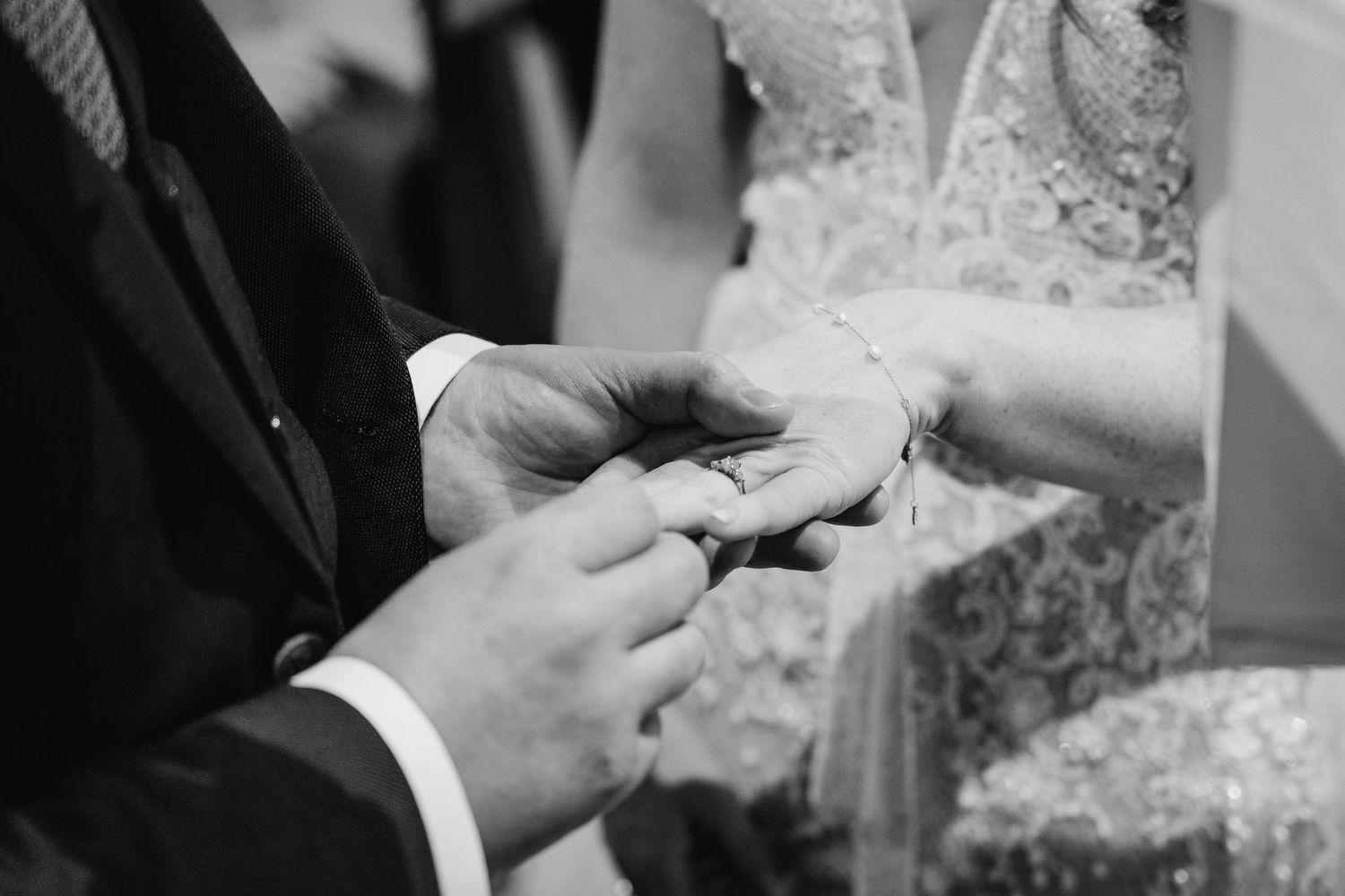 Black and white close-up shots of hands exchanging wedding rings during a ceremony.