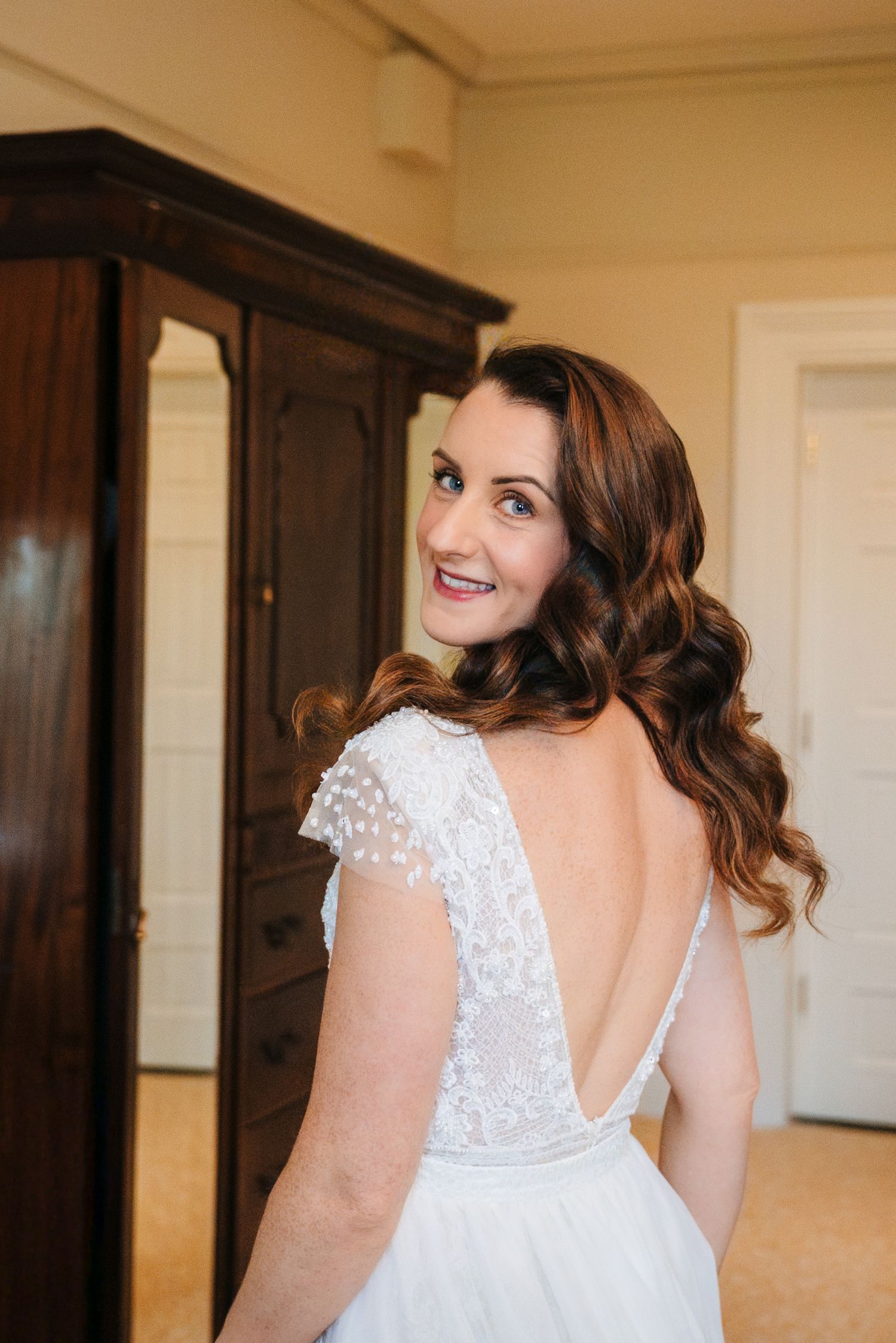 Close-up details of a white lace wedding dress with delicate cap sleeves and an elegant open back design.